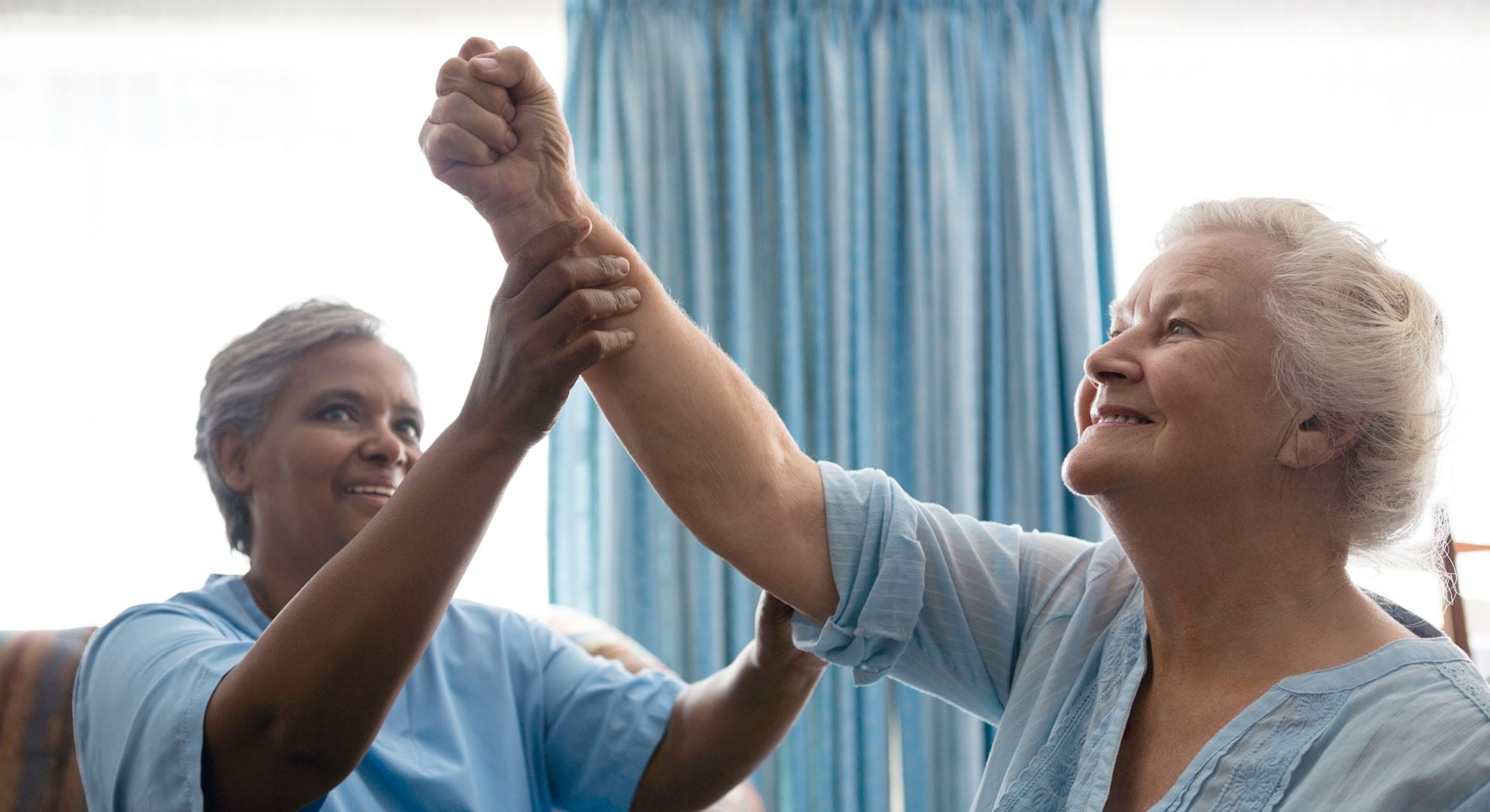 An Aid helps a elderly woman raise her left arm